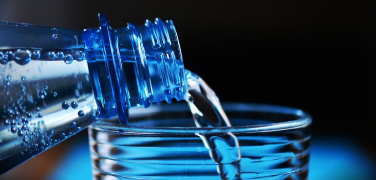 Wasser aus Flasche wird in Glas zum Trinken vorbereitet